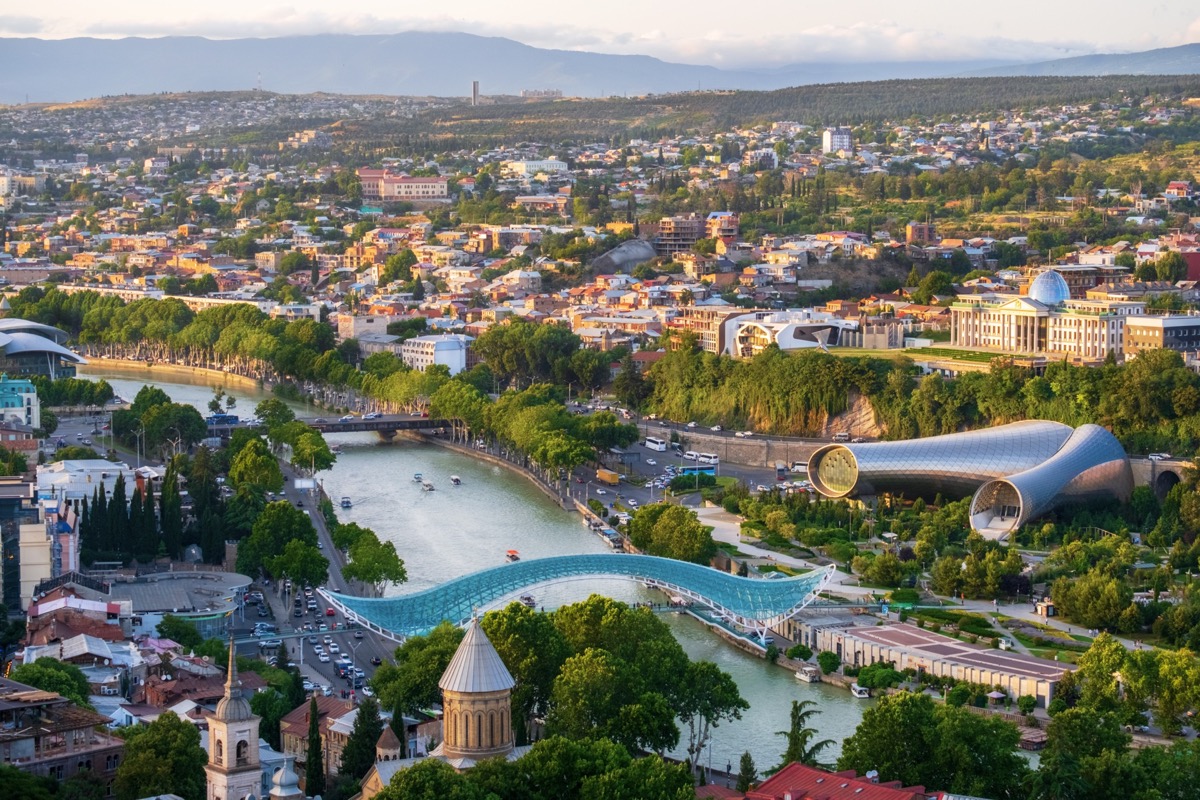 Aerial view of Tbilisi, Georgia at sunset, with the Peace Bridge over the Mtkvari river